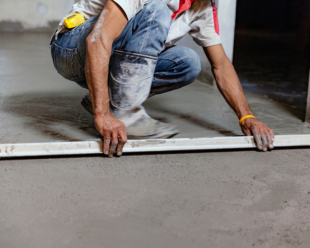 A man kneeling down on the ground holding a ruler.